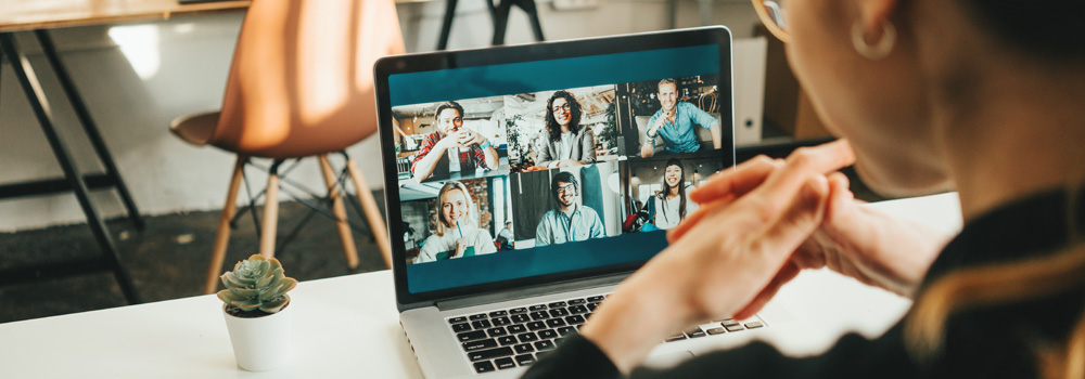 Woman has video conference with her remote team using laptop and camera